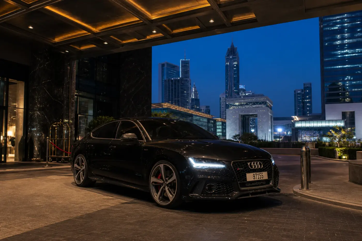 Audi rental Dubai guide hero with a dark Audi RS7 at a DIFC hotel porte-cochère at blue hour
