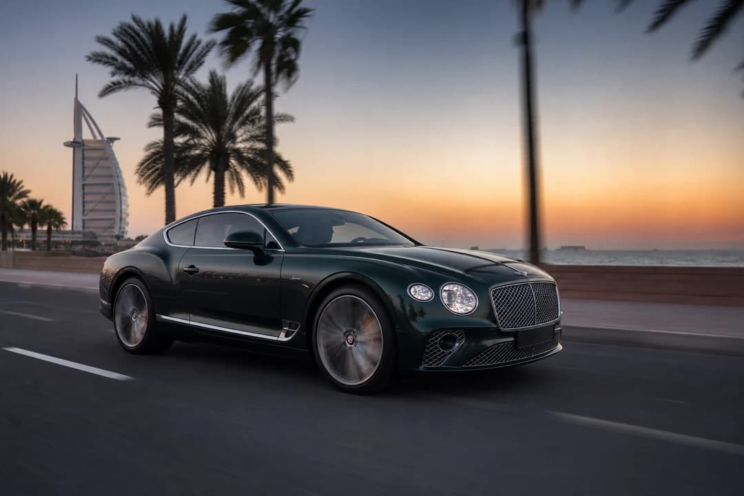 Rent Bentley Dubai: British racing green Continental GT Speed on Jumeirah Beach Road at dusk