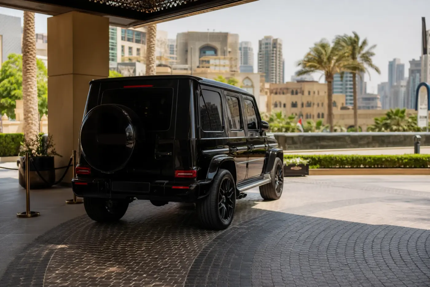 Best luxury cars Dubai summer heat hero with a closed Mercedes-Benz G63 in harsh midday light outside a Downtown hotel