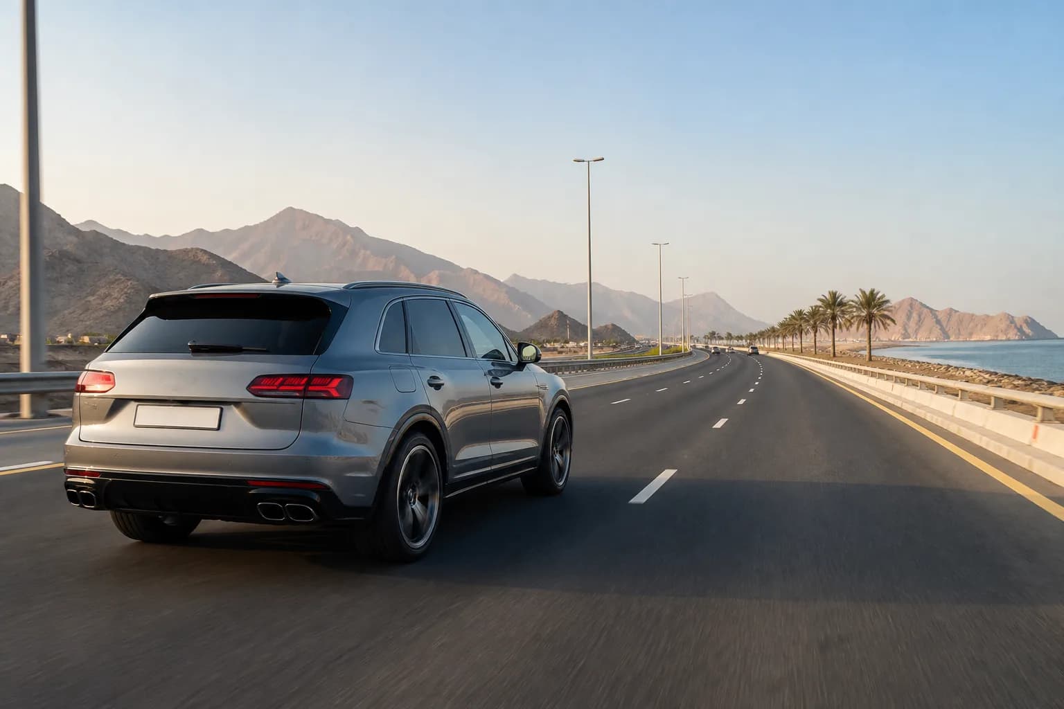 Dubai to Ajman luxury car rental: luxury SUV on a northern UAE dual carriageway toward the Ajman coast