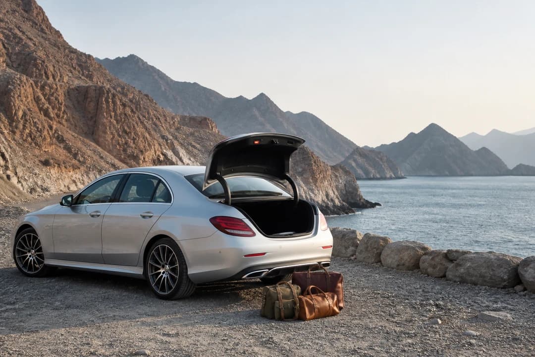 Luxury sedan at a rocky Fujairah coastal overlook for UAE road trip rental coast and mountain days