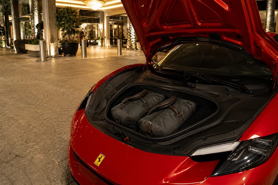 Ferrari 296 GTS front luggage with soft cabin bags at a Dubai hotel porte-cochere for two-seat packing