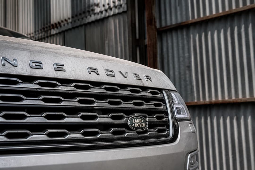 Range Rover grille against corrugated Al Quoz warehouse steel for luxury car rental Al Quoz Dubai