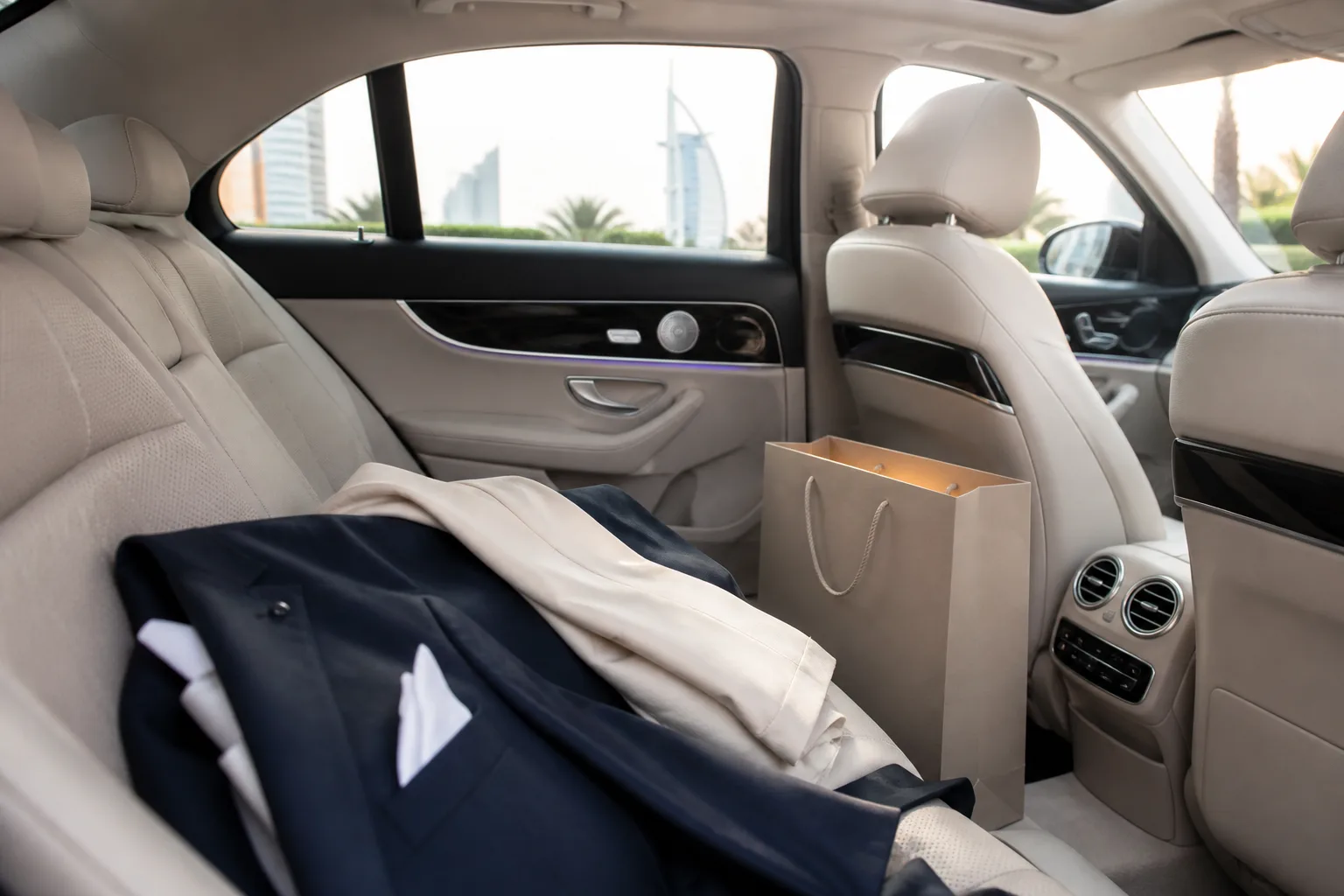 Quiet luxury sedan rear cabin with soft formal jackets for wedding guest hops in Dubai