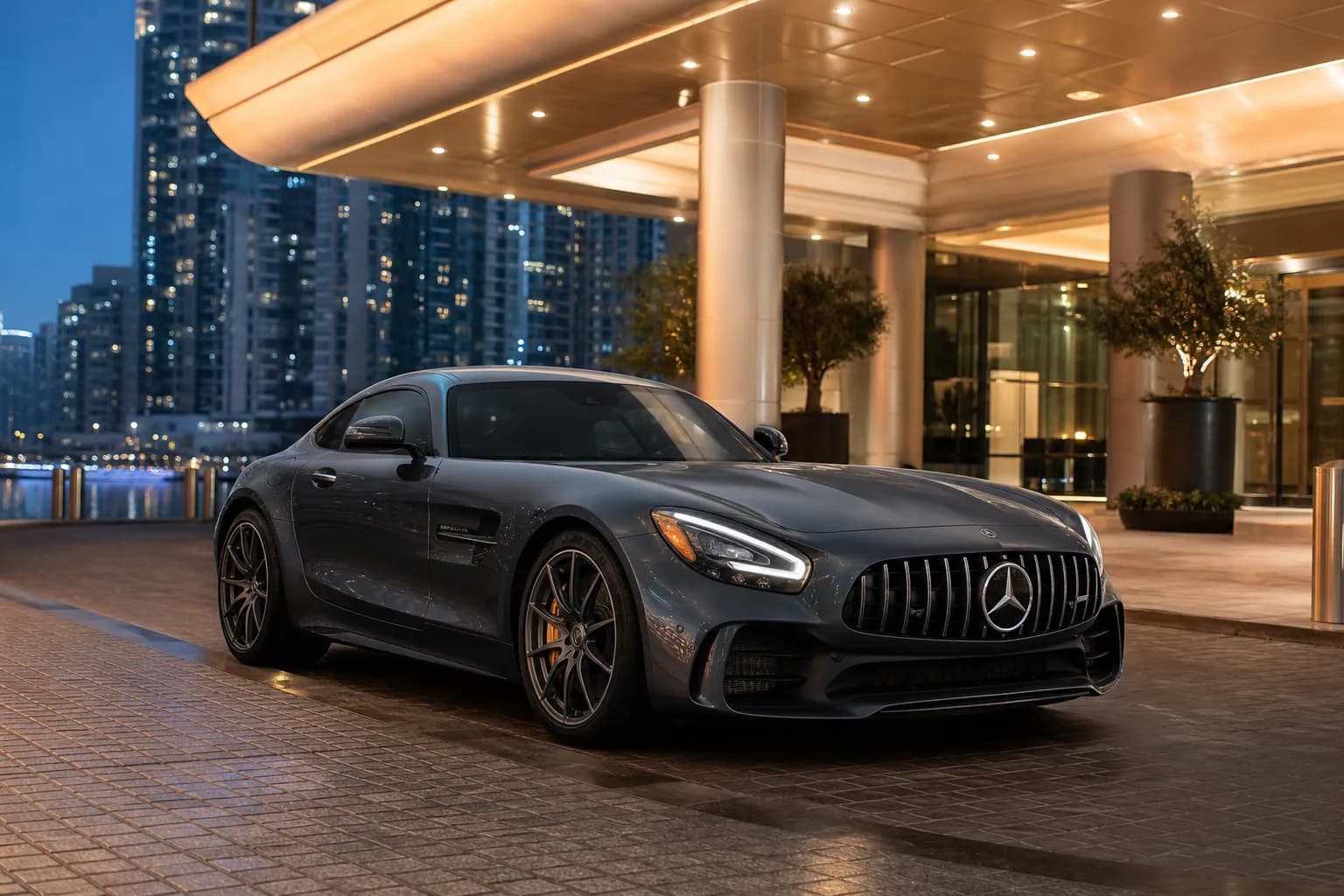 Mercedes AMG GT rental Dubai hero with a dark AMG GT coupe at a Marina hotel porte-cochère at blue hour
