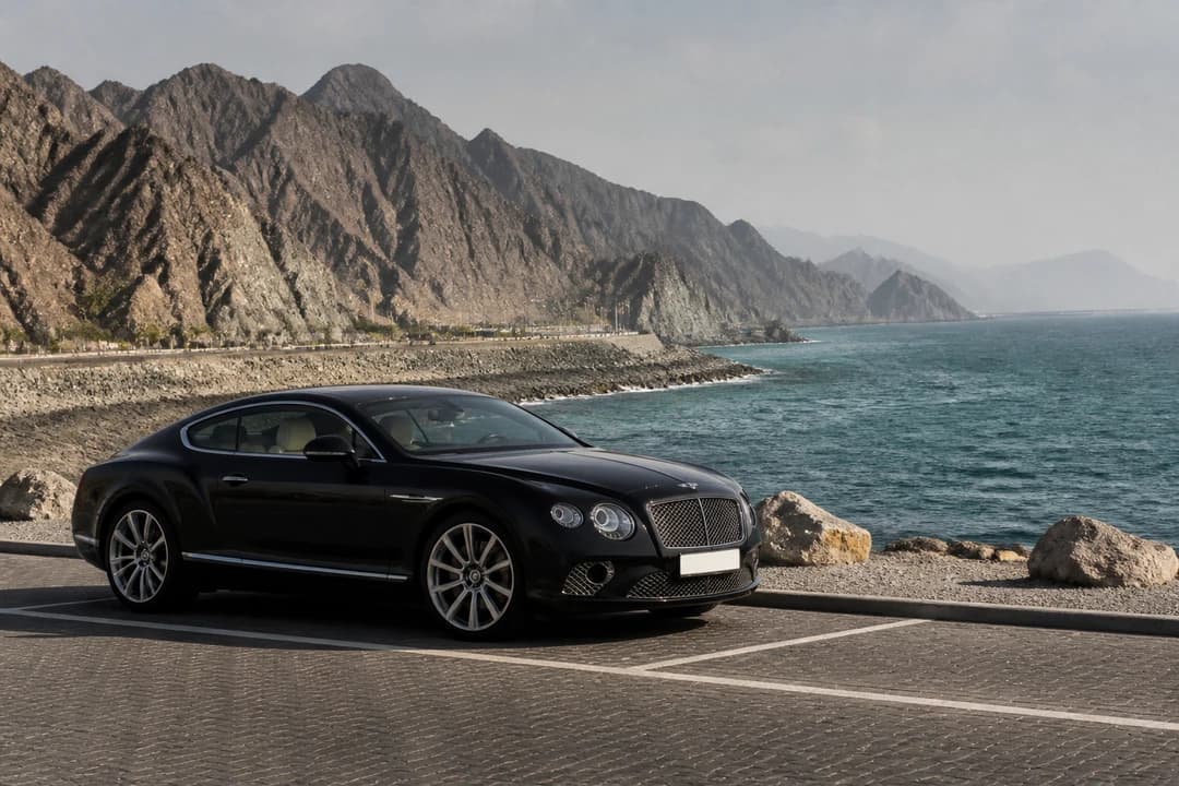 UAE road trip rental: grand tourer at a Fujairah coastal overlook on an east-coast day from Dubai
