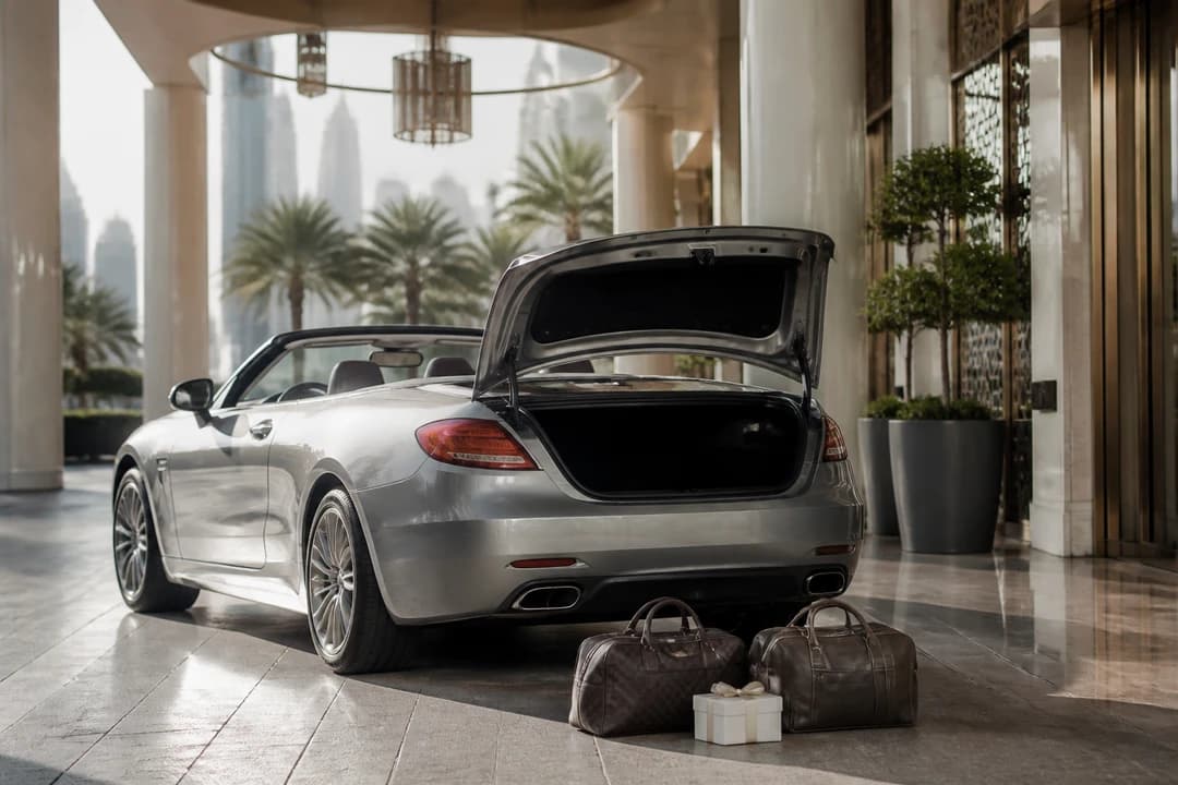 Soft overnight bags and a gift box beside a convertible boot for best cars to rent Dubai couples packing