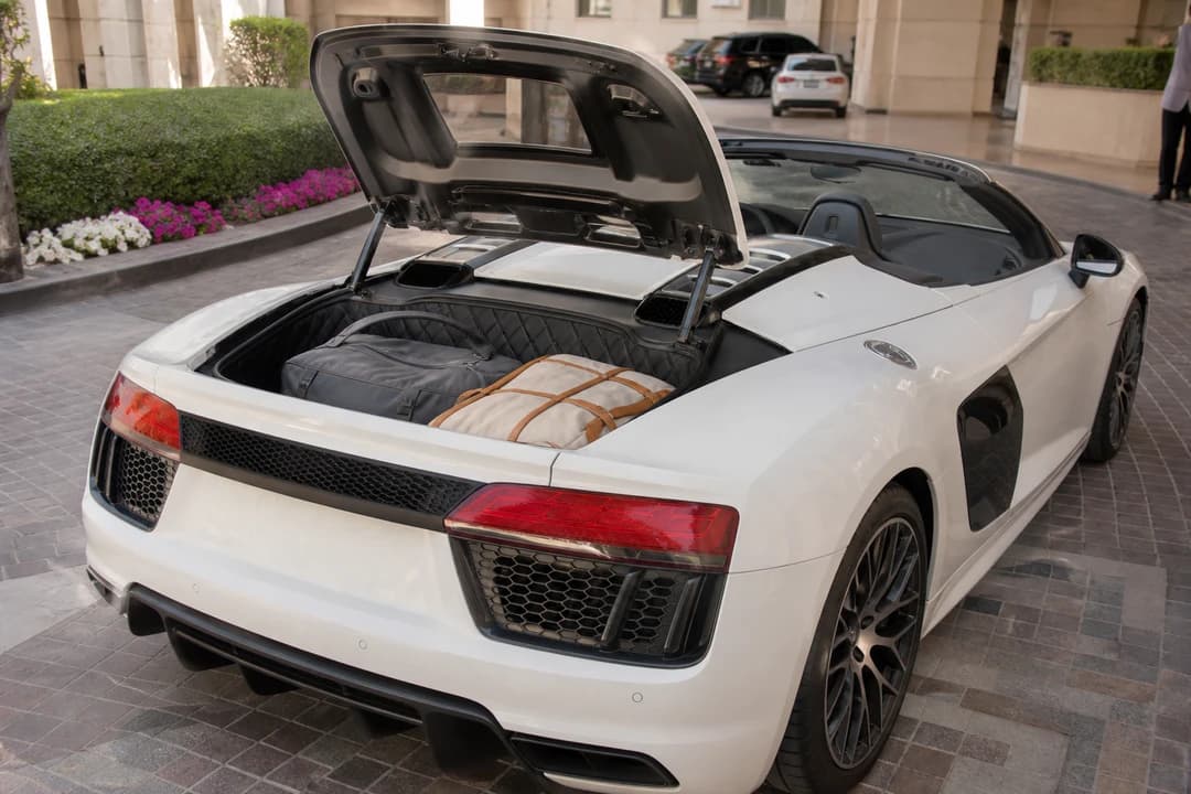 Audi R8 Spyder boot with soft cabin bags at a Dubai hotel driveway for luxury car rental Dubai packing