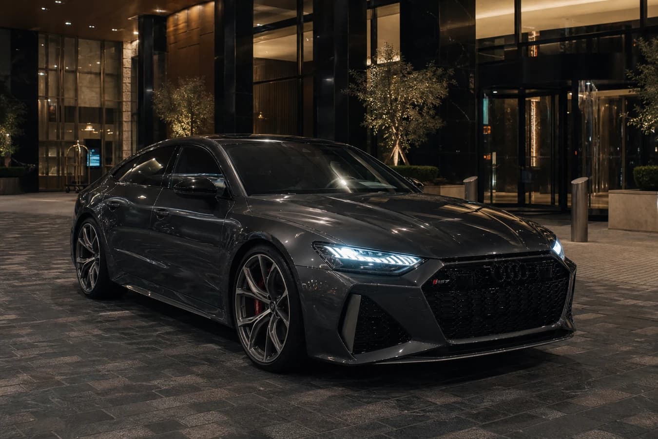 Audi RS7 rental Dubai hero with a dark RS7 Sportback at a DIFC hotel porte-cochère at blue hour