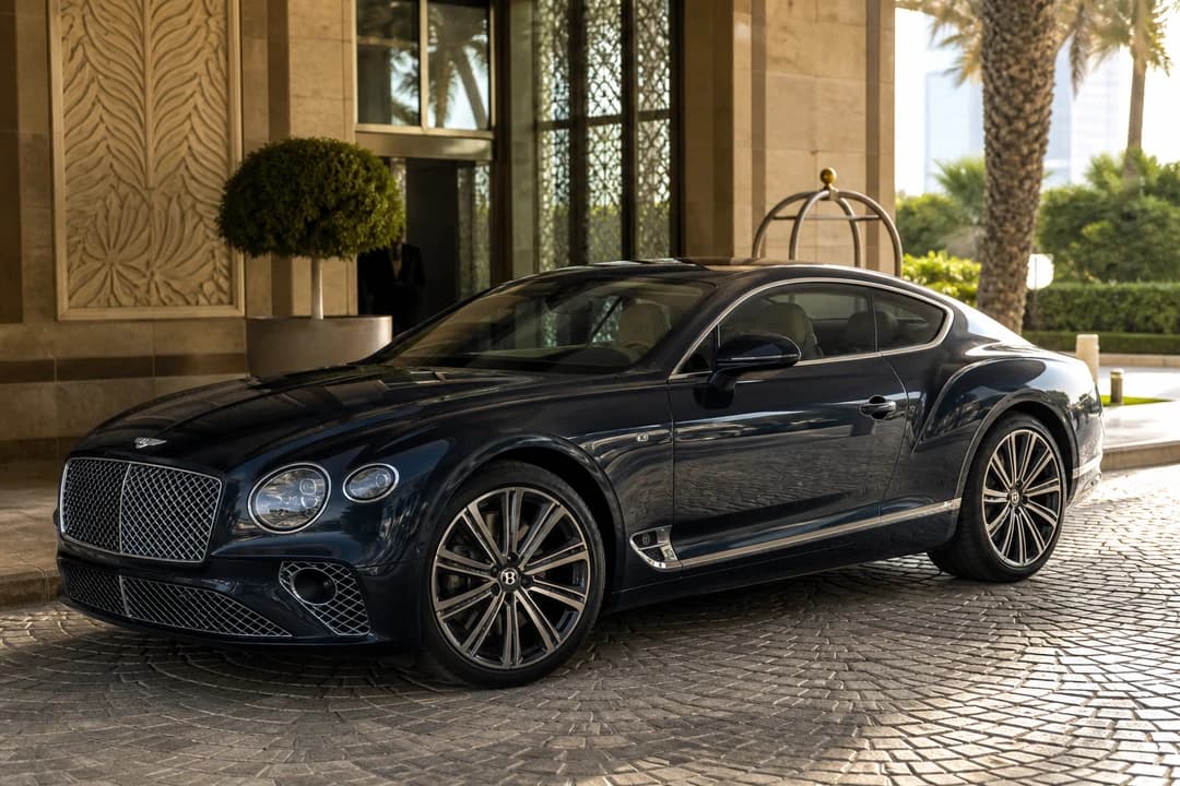 Rent Bentley Continental GT Dubai: dark Continental GT Speed at a Palm Jumeirah hotel porte-cochère in afternoon light