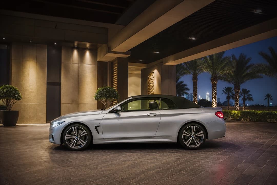 Rent BMW 440i Convertible Dubai: side profile at a Downtown hotel porte-cochère at dusk