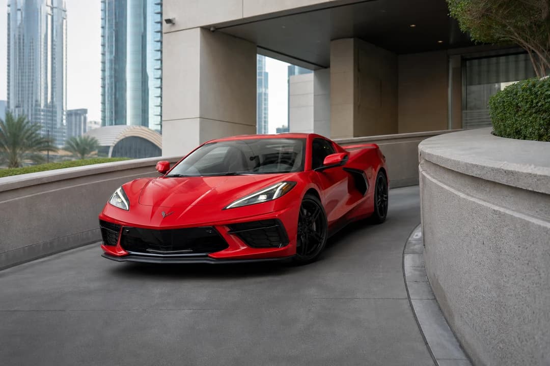 Rent Corvette Dubai: red Corvette Stingray clearing a tight Downtown hotel ramp with a low mid-engine nose