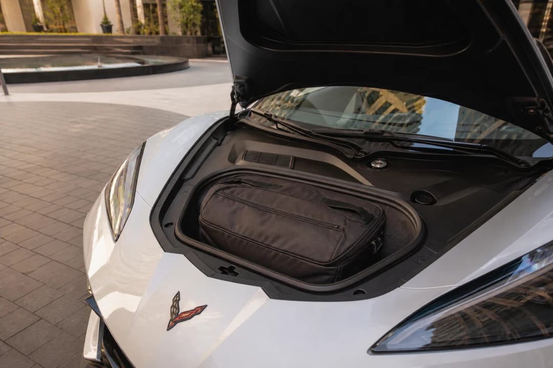 Corvette frunk with a soft cabin bag at a Marina hotel driveway for sports car rental Dubai packing