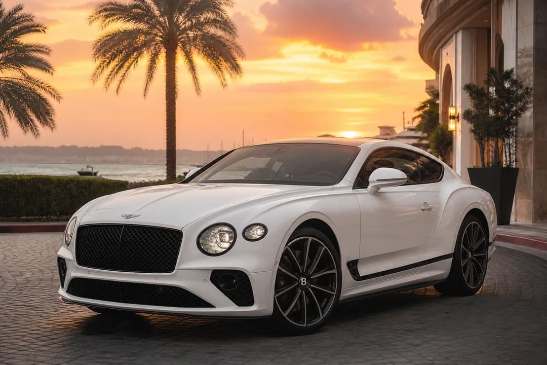 White Bentley Continental GT Speed at a Palm Jumeirah hotel forecourt for supercar rental Dubai coastal evenings
