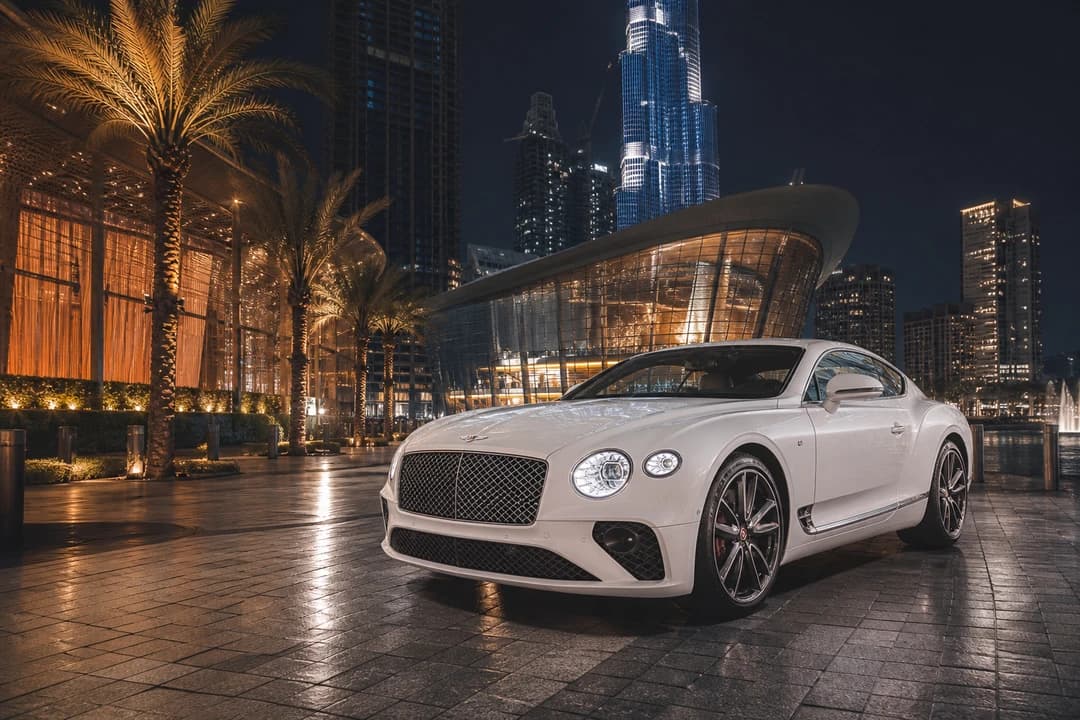 Bentley Continental GT near Dubai Opera district lights for luxury car rental Dubai evening arrivals