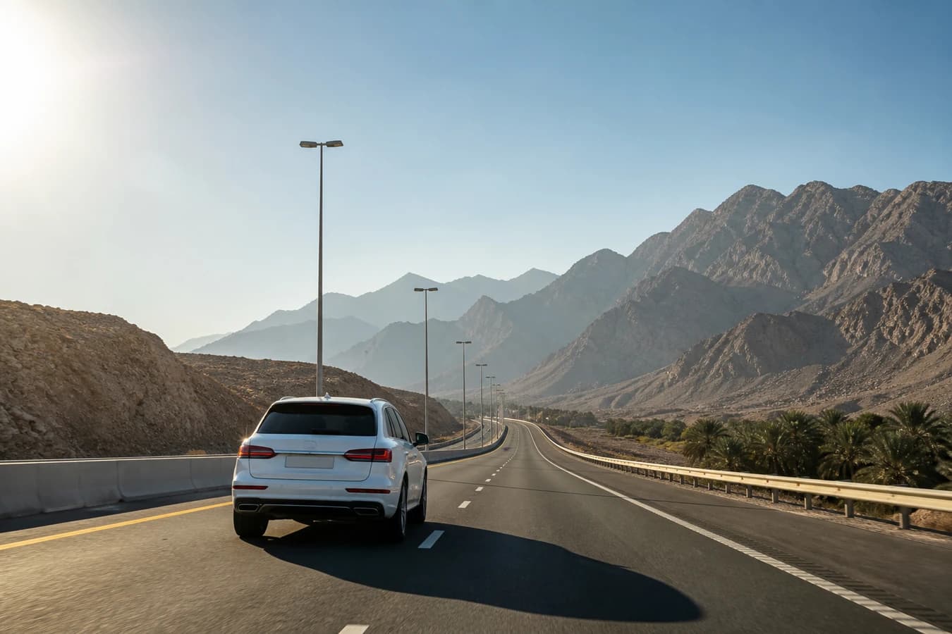 Dubai to Ras Al Khaimah luxury road trip: luxury SUV on a northern UAE dual carriageway with Hajar foothills ahead