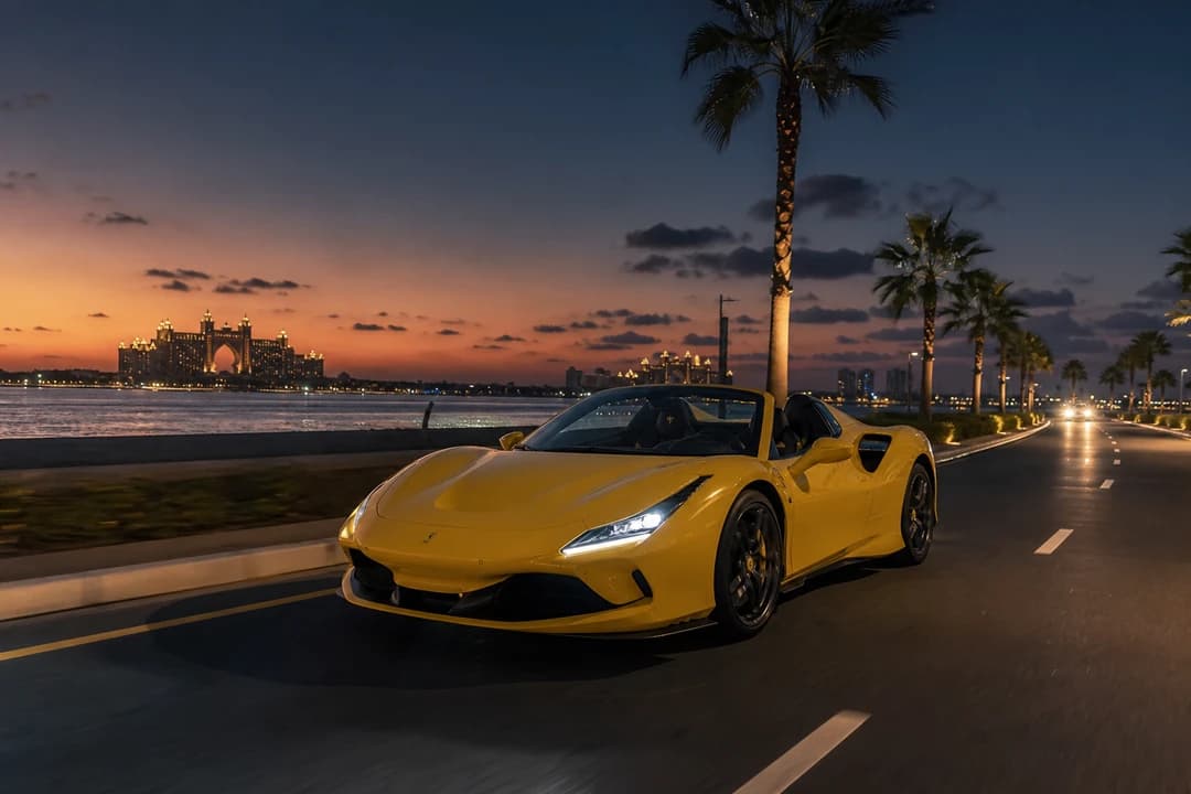 Yellow Ferrari spider roof-down on Palm Jumeirah after sunset for supercar rental Dubai open-top theatre