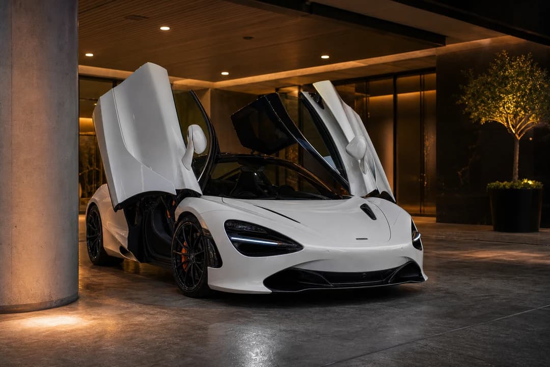Rent McLaren 720S Dubai: white 720S Coupe clearing a tight Downtown valet bay with dihedral doors raised