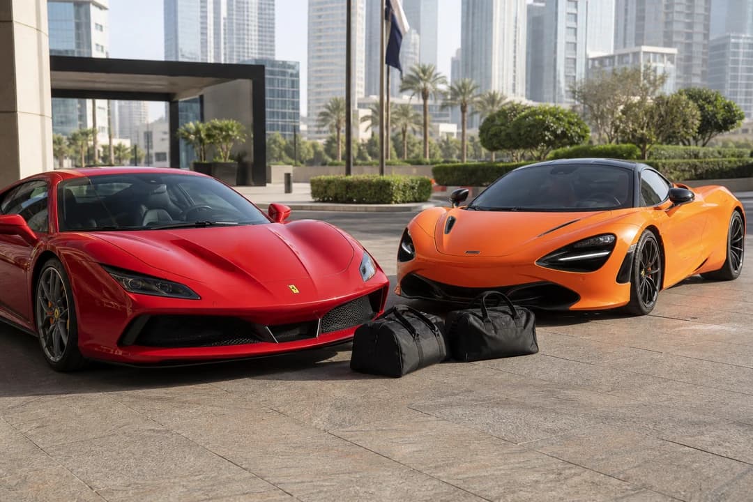 Ferrari F8 Tributo and McLaren 720S at a DIFC kerb with two soft duffels for luxury car hire Dubai packing