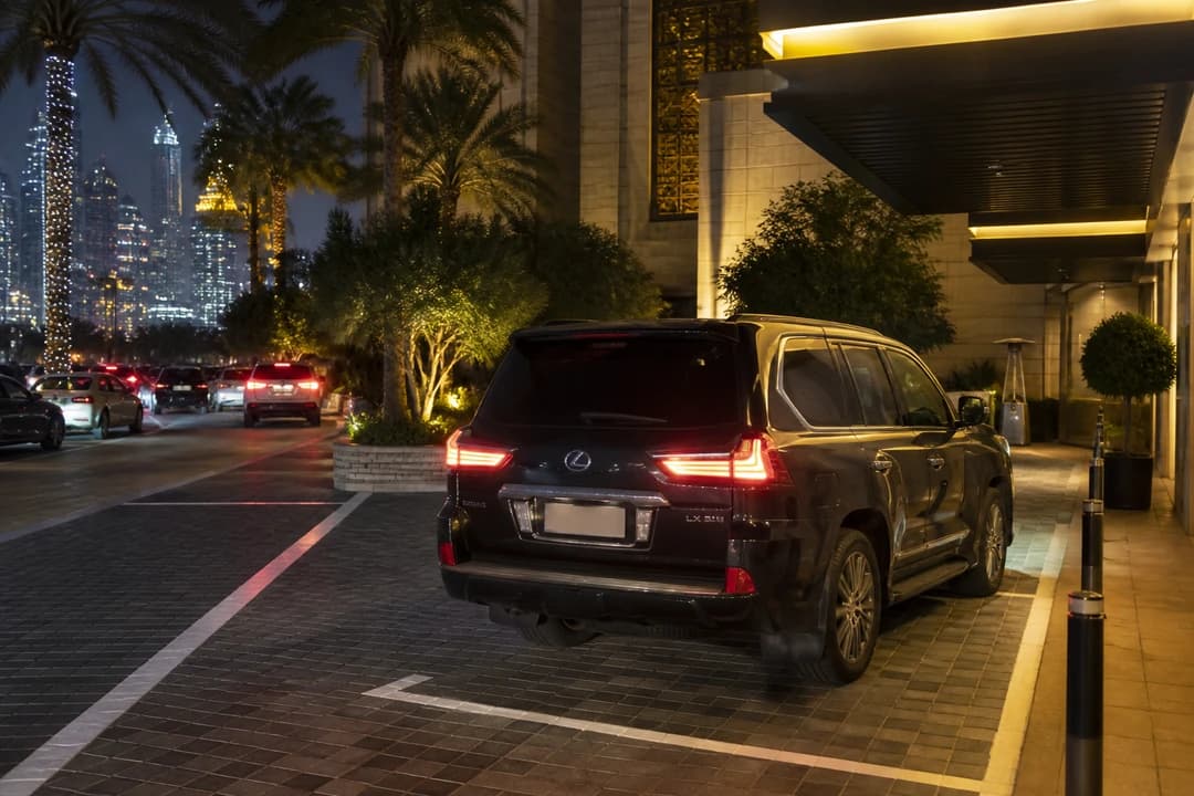 Dubai car hire luxury SUV in a marked hotel parking bay on New Year’s Eve while city lights suggest crowded streets