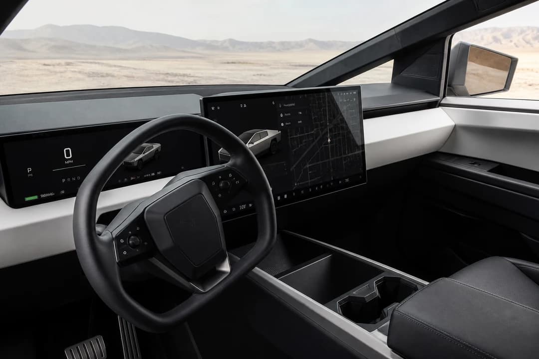 Tesla Cybertruck minimalist cockpit interior with large horizontal touchscreen and driver-focused steering wheel