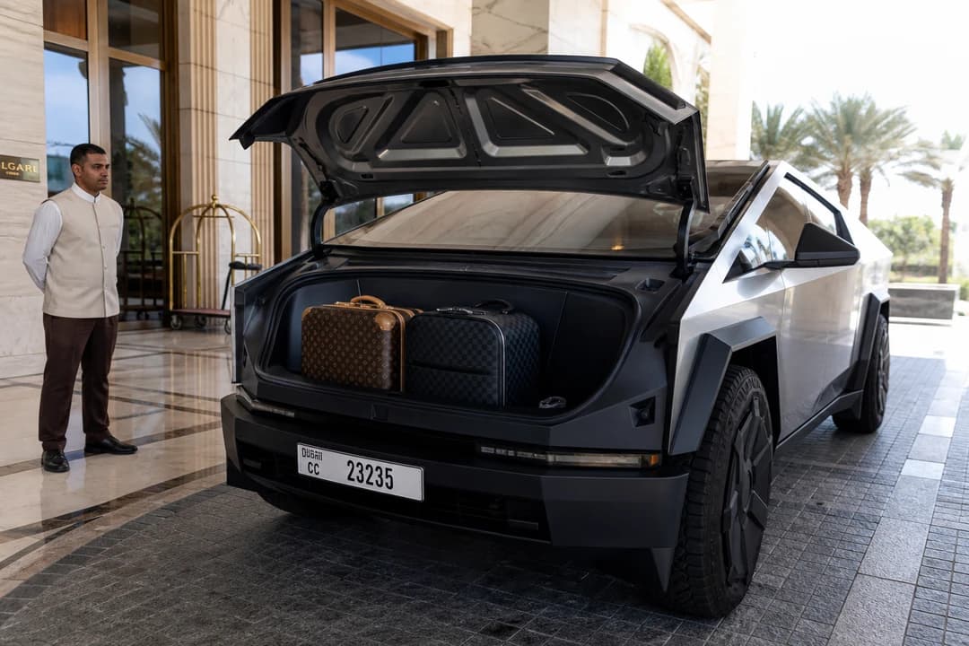 Tesla Cybertruck open frunk loaded with designer luggage at a Dubai hotel porte-cochère with concierge attendant