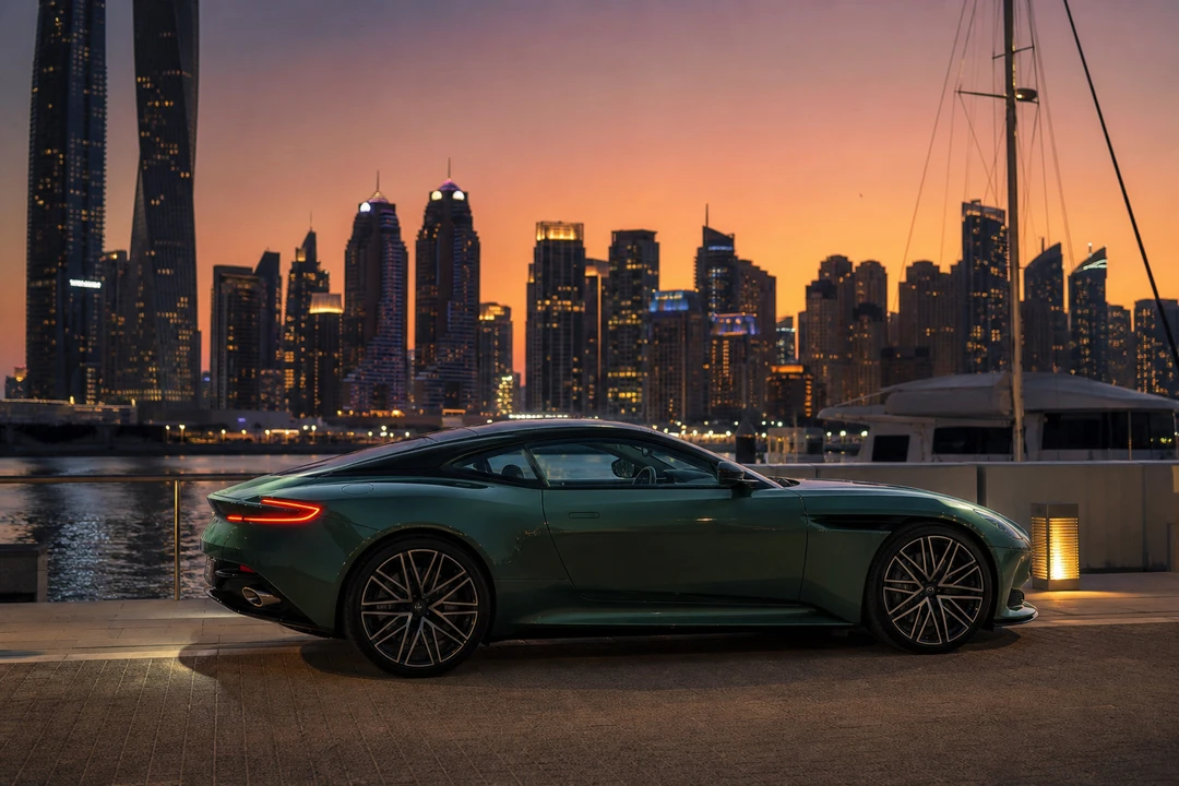 Aston Martin DB12 beside Dubai Marina yachts at dusk for exotic car rental Dubai evening arrivals