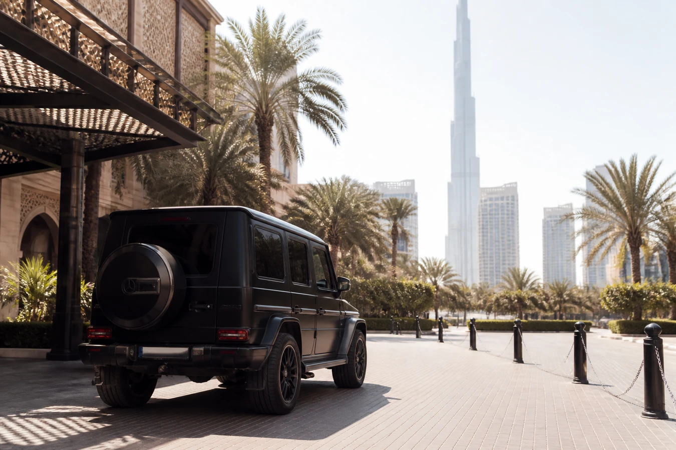 Dubai summer luxury car rental prices: a closed-roof Mercedes-Benz G63 in harsh midday light outside a Downtown hotel