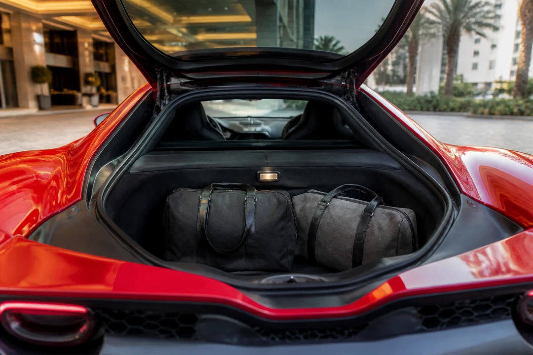 Open Ferrari 296 boot with overnight bags at a Dubai hotel kerb before an Eid stay