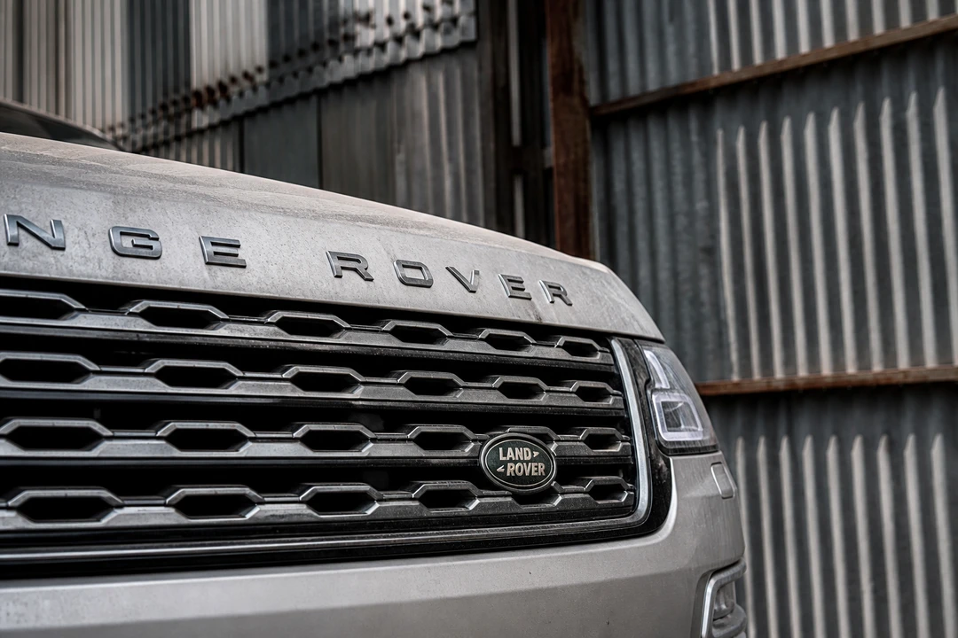 Range Rover grille against corrugated Al Quoz warehouse steel for luxury car rental Al Quoz Dubai
