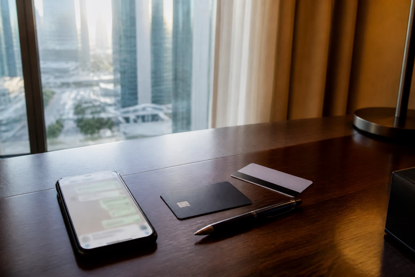 Luxury car rental Dubai debit card: WhatsApp quote and a debit card on a DIFC hotel desk before handover