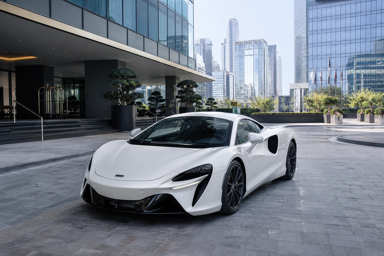 McLaren rental Dubai guide hero with a silica white Artura Coupe at a DIFC hotel porte-cochère in morning light