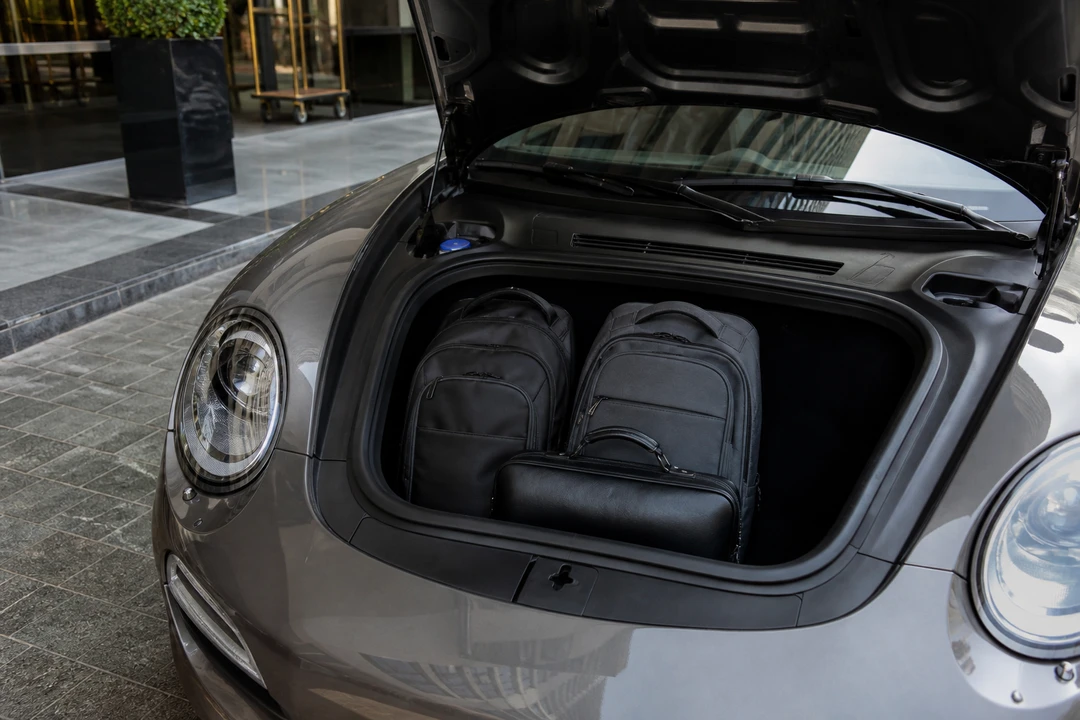 Porsche 911 Turbo S front boot with backpacks at a Dubai hotel kerb for luxury car hire Dubai two-bag packing