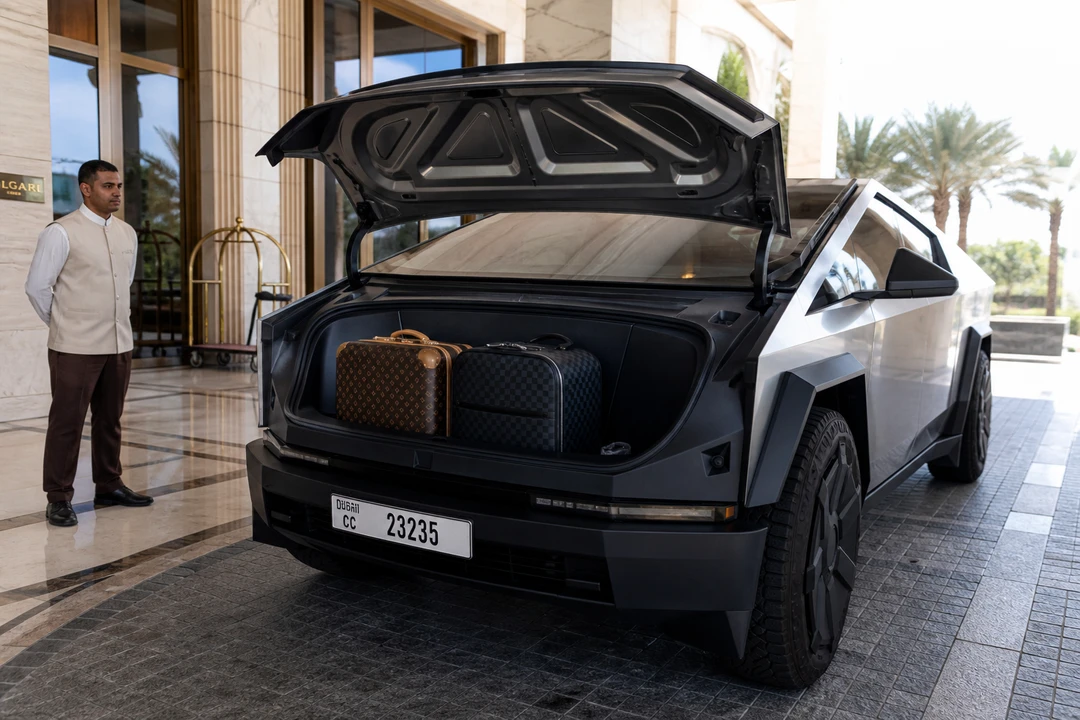 Tesla Cybertruck open frunk loaded with designer luggage at a Dubai hotel porte-cochère with concierge attendant